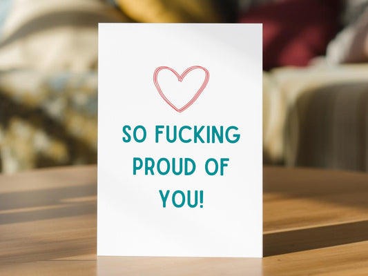 A proud of you, congratulations card featuring a pink outlined heart and the text 'SO FUCKING PROUD OF YOU!' in teal. 