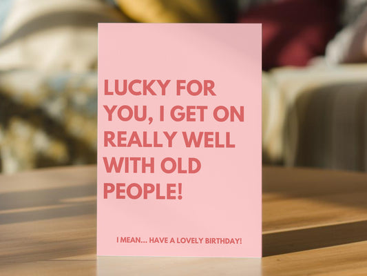 A pink greeting card that reads, 'LUCKY FOR YOU, I GET ON REALLY WELL WITH OLD PEOPLE! I MEAN.