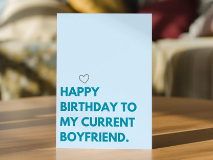 A light blue boyfriend birthday card with the text 'HAPPY BIRTHDAY TO MY CURRENT BOYFRIEND.' in teal and a small heart outline above.
