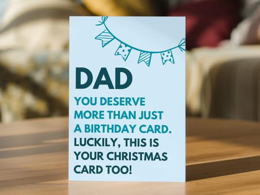 A light blue dad birthday card with dark teal text reading 'DAD YOU DESERVE MORE THAN JUST A BIRTHDAY CARD. LUCKILY, THIS IS YOUR CHRISTMAS CARD TOO!' 